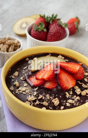 Brasilianische typische acai Schale mit Früchten und Müsli auf Holzgrund. Stockfoto