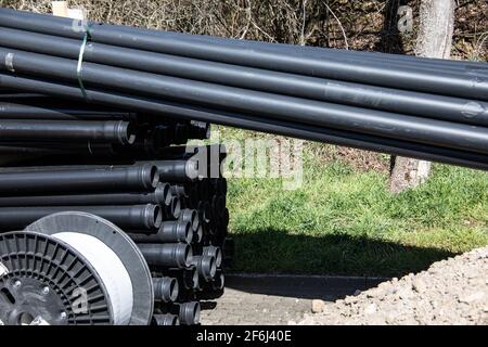 Lange schwarze Kunststoffrohre auf einer Baustelle Stockfoto