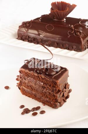 Ein stilvoller Schokoladenkuchen und ein Stück davon davor. Stockfoto