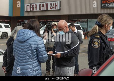 Mitarbeiter von Sécurité Publique überreichen einem Trainer von Mega Gym 24h die offiziellen Dokumente für die obligatorische Schließung seines Fitnessstudios nach einem schweren COVID 19-Ausbruch in Quebec City, 31. März 2021. Stockfoto