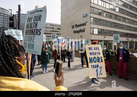 London, Großbritannien. April 2021. NHS-Mitarbeiter protestierten gegen die vorgeschlagene Gehaltserhöhung um 1 % von der Regierung außerhalb des St. Thomas’ Hospital, Westminster Bridge Road, London, Großbritannien. Auf den Plakaten steht: „Zahlen Sie unsere Mitarbeiter im Gesundheitswesen, schlagen Sie um zu gewinnen“ und „Wir sind mehr als 1 % wert“. Kredit: Joshua Windsor/Alamy Live Nachrichten Stockfoto