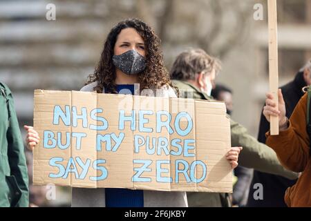 London, Großbritannien. April 2021. Ein Protestler mit einem Plakat mit der Aufschrift „NHS Hero But My Purse Says Zero“. NHS-Mitarbeiter protestierten gegen die vorgeschlagene Gehaltserhöhung um 1 % von der Regierung außerhalb des St. Thomas’ Hospital, Westminster Bridge Road, London, Großbritannien. Kredit: Joshua Windsor/Alamy Live Nachrichten Stockfoto