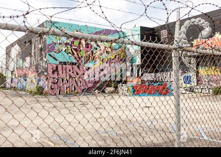 Blick durch einen Zaun mit Stacheldraht auf Street Art, die jede Wand im Wynwood Art District, Miami, Florida, USA, abdeckt Stockfoto