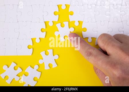 Hand setzen das ein Stück weißes Puzzle auf Farbe Hintergrund und Ort für Ihre Inhalte Stockfoto