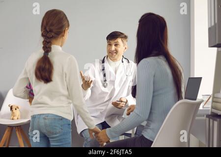 Der Kinderarzt spricht mit einem kleinen Mädchen und ihrer Mutter im Büro einer medizinischen Klinik. Stockfoto