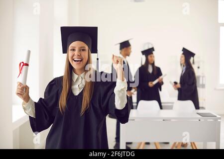 Eine begeisterte Studentin, die ihr Diplom hält und die Hochschule oder Universität feiert Abschluss Stockfoto