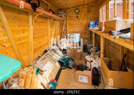 Das Innere eines halb leeren, aber chaotischen Holzgartenschuppen oder Werkzeugschuppens in Großbritannien. Stockfoto