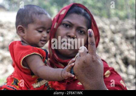 Nandigram, Indien. April 2021. Eine Frau mit ihrem Kind zeigt ihren angewinkelten Finger, nachdem sie bei East Midnapur ihre Stimme abgegeben hat.die Wähler von Nandigram haben ihre Stimme während der zweiten Phase der Parlamentswahlen in Westbengalen abgegeben, um die Wahlen friedlich zu gestalten. (Foto von JIT Chattopadhyay/SOPA Images/Sipa USA) Quelle: SIPA USA/Alamy Live News Stockfoto