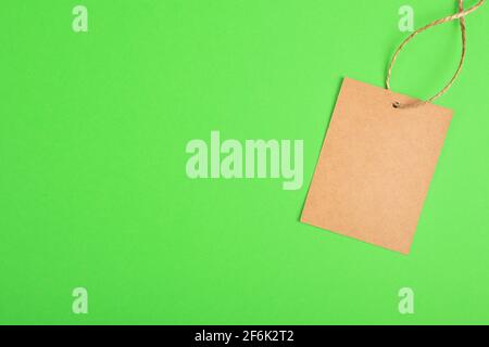 Craftbrauner Papieranhänger isoliert auf grünem Hintergrund. Sale-Preis-Banner mit Kopieplatz in minimalem Stil Stockfoto