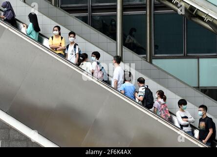 Hongkong, China. April 2021. Menschen mit Gesichtsmasken nehmen in Hongkong, Südchina, am 1. April 2021 eine Rolltreppe mit. Das Hongkonger Zentrum für Gesundheitsschutz (CHP) meldete am Donnerstag 13 weitere bestätigte Fälle von COVID-19, was einer Gesamtzahl von 11,480 entspricht.von den neuen Fällen wurden 11 importiert und zwei wurden lokal übertragen und hatten unbekannte Ursprünge, so eine Stellungnahme des CHP. Quelle: Lo Ping Fai/Xinhua/Alamy Live News Stockfoto