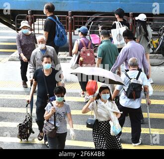 Hongkong, China. April 2021. Menschen mit Gesichtsmasken gehen auf einer Straße in Hongkong, Südchina, 1. April 2021. Das Hongkonger Zentrum für Gesundheitsschutz (CHP) meldete am Donnerstag 13 weitere bestätigte Fälle von COVID-19, was einer Gesamtzahl von 11,480 entspricht.von den neuen Fällen wurden 11 importiert und zwei wurden lokal übertragen und hatten unbekannte Ursprünge, so eine Stellungnahme des CHP. Quelle: Lo Ping Fai/Xinhua/Alamy Live News Stockfoto