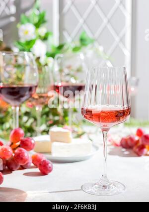 Roze Wein in einem Glas auf einem hellen Betongrund in den Strahlen der Sonne. Selektiver Fokus Stockfoto