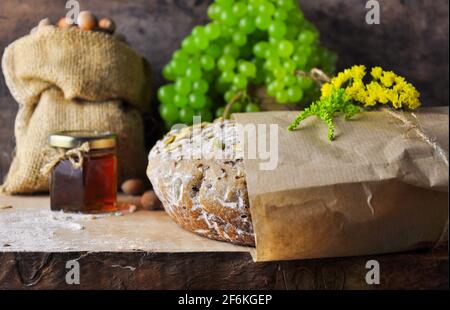 Brot. Verpackung in einer Papiertüte mit Blumen. Frühstück Komposition auf einem Holzbrett. Stockfoto