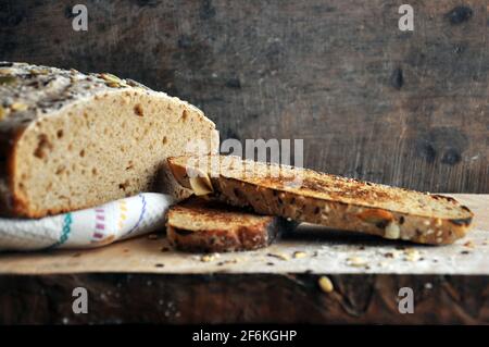 Frisch gebackenes, geschnittenes Brot auf einem rustikalen Holzbrett. Сlose nach oben. Platz für Ihr Logo Stockfoto