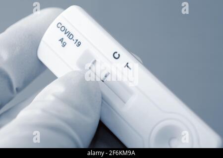 Hand in medizinische Handschuhe hält negativen Antigen-Schnelltest für die Erfassung von COVID-19-Antikörpern. Es zeigt ein negatives Ergebnis. Stockfoto