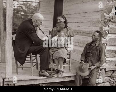 Dr. S.A. Malloy untersucht Louis Graves und seine Familie auf ihrer Veranda. Sie sind Kreditnehmer der FSA (Farm Security Administration). Caswell County, North Carolina. 1940. Stockfoto