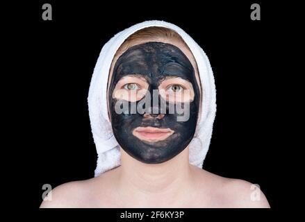 Junge Frau mit einer kosmetischen Peeling-Maske mit Aktivkohle auf ihrem Gesicht. Gesichtspflege. Stockfoto