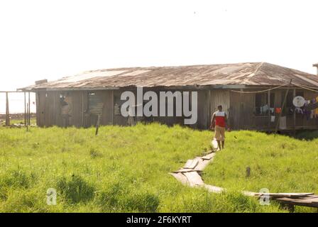 Mann, der durch eine hölzerne Fußgängerbrücke in Ayetoro, Gemeinde Ilaje, Bundesstaat Ondo, Nigeria, läuft. Stockfoto