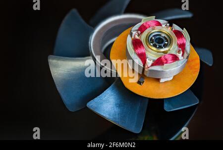 Integrierter Hall-Sensor im Computer-Lüfterrotor und Kunststoffflügel auf schwarzem Hintergrund. Rote Coils Kupferdrahtwicklung oder Kugellager im EC-Elektromotor. Stockfoto