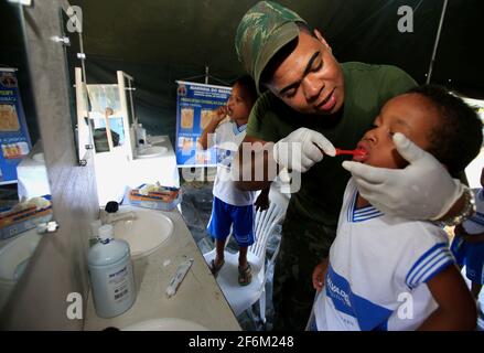 salvador, bahia / brasilien - 4. november 2015: Ein Militärangehöriger der brasilianischen Marine lehrt ein Kind, sich während der sozialen Aktion auf der Insel die Zähne zu putzen Stockfoto