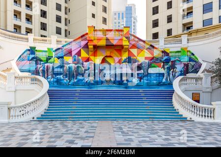 Dubai, VAE, 22.02.2021. Ein Meer von Pferden Bunte Wandgemälde mit Straßenkunst auf einer palastartigen Treppe auf dem JBR The Walk, mit Pferden, die im Meer galoppieren. Stockfoto