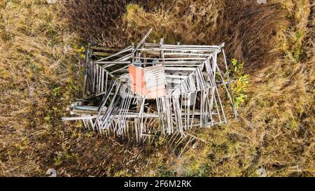 Draufsicht auf das Dielendach eines zerstörten Hauses. Ein verlassene Holzgebäude steht allein auf einem leeren Grundstück. Foto von Ruinen, die Sehnsucht und Traurigkeit hervorrufen. Stockfoto