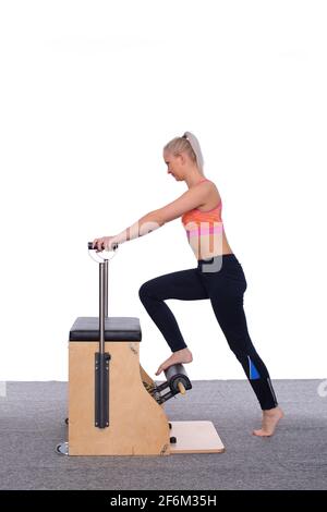 Ein junger erfahrener Trainer demonstriert, wie man Pilates richtig übt An der Maschine Stockfoto