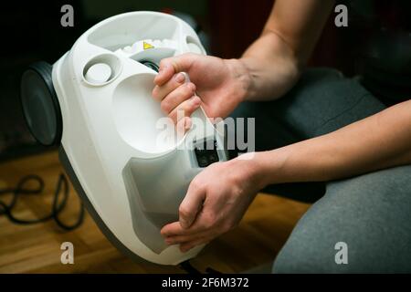 Der Prozess der Reinigung von Teppichen mit einem Dampfstaubsauger. Die Hände eines Reinigungsarbeiters bereiten die Ausrüstung für die Arbeit vor. Stockfoto