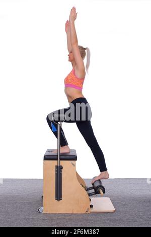 Der Pilates-Trainer demonstriert, wie bestimmte Bein- und Armmuskeln auf einem ausgewählten Gerät trainiert werden. Stockfoto