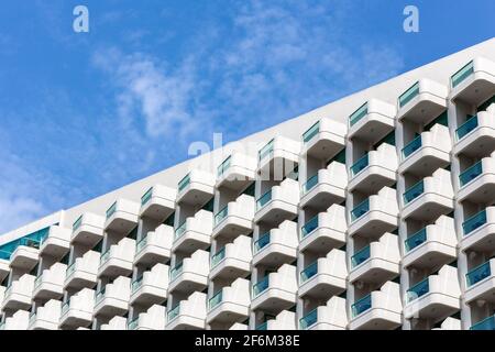 Reihen und Muster von identischen kleinen Balkonen eines modernen Luxushotels in Dubai, die geometrische Muster bilden, mit blauem Himmel im Hintergrund, diagonal Stockfoto