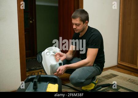 Der Prozess der Reinigung von Teppichen mit einem Dampfstaubsauger. Ein Mitarbeiter eines Reinigungsunternehmens bereitet die Geräte auf die Arbeit vor. Stockfoto