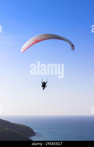 Gleitschirmfliegen über üppige grüne Berge vom Aussichtspunkt auf Koh Larn Island in Pattaya, Chonburi Thailand. Stockfoto