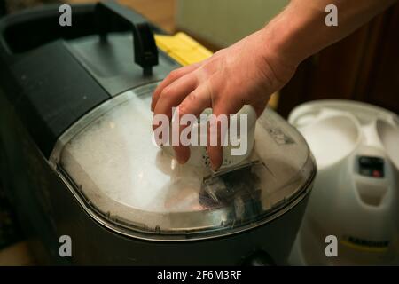 Der Prozess der Reinigung von Teppichen mit einem Dampfstaubsauger. Gerätekapazität mit verschmutzter Lösung nach der Reinigung. Stockfoto