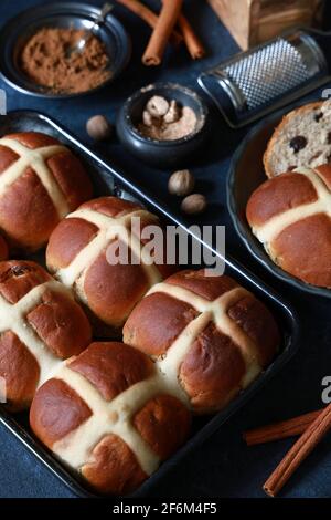 Frisch gebackene hausgemachte Hot Cross Buns für Karfreitag Ostern Feierlichkeiten mit Gewürzen auf dunkelblauem Hintergrund Stockfoto