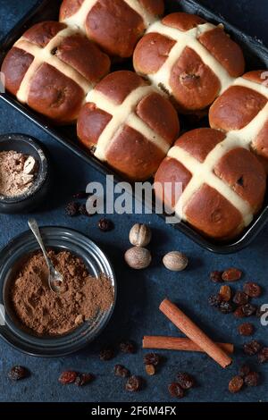 Frisch gebackene hausgemachte Hot Cross Buns mit Gewürzen im Dunkeln Blauer Hintergrund Stockfoto