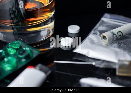 Kokain, Pillen, Alkohol und Heroin in einer Spritze. Drogenabhängigkeit. Konzept der Stopp-Medikamente. Selektiver Fokus auf Pillen. Stockfoto