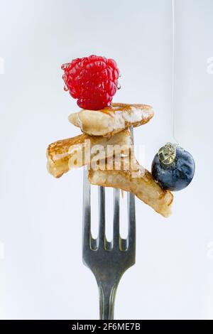 Pfannkuchen auf einer Gabel mit Erdbeeren auf weißem Hintergrund. Stockfoto