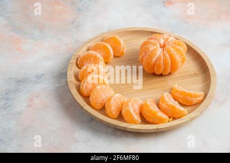 Geschälte Mandarinen aus Clementinen auf Holzplatte auf dem Hintergrund Stockfoto