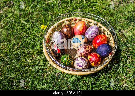 Unschärfe-Effekte bei mehrfarbigen ostereiern. Dekoriert pysanka und krashanka. Holzkorb Mit Ostereiern Im Grünen Gras. Nahaufnahme. Draufsicht. Festlich. dan Stockfoto