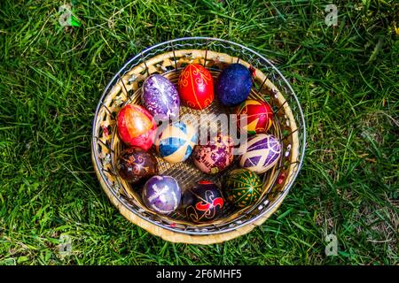 Unschärfe-Effekte bei mehrfarbigen ostereiern. Dekoriert pysanka und krashanka. Holzkorb Mit Ostereiern Im Grünen Gras. Nahaufnahme. Draufsicht. Handgefertigter dez Stockfoto
