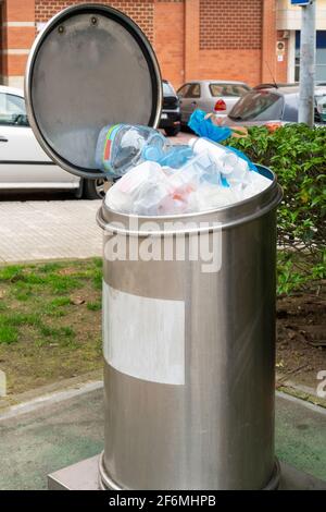 Müllcontainer aus Metall mit Plastikmüll auf einer Straße in der Stadt. Sammelstelle für ortsfeste Abfälle. Deckel des zu gefüllten Behälters geöffnet. Stockfoto