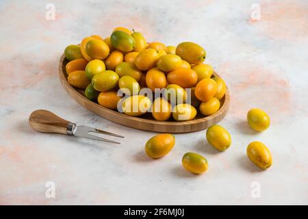 Haufen leckerer Kumquats auf Holzplatte Stockfoto