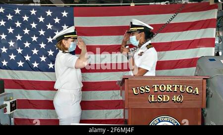 US Navy Cmdr. Kimberly Jones, der neue Kommandant des Docks der Whidbey Island-Klasse USS Tortuga, begrüßt den scheidenden Cmdr. Rosie Goscinski während der Befehlswechselzeremonie am 16. Juli 2020 in Virginia Beach, Virginia. Stockfoto