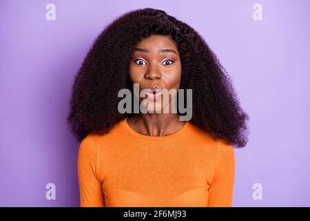 Foto von süßen ziemlich dunklen Haut Dame tragen orange Hemd Beeindruckter isolierter violetter Hintergrund Stockfoto