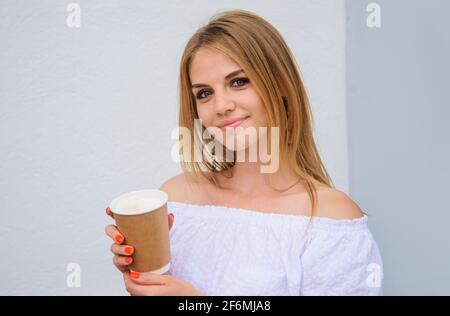 Lächelndes Mädchen mit Kaffee oder Tee in Papiertasse. Kaffee zum trinken. Zum Mitnehmen. Heiße Getränke. Espresso, Latte, Cappuccino. Stockfoto