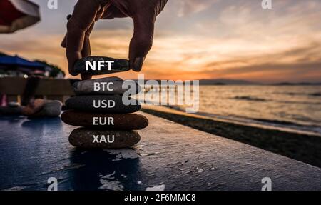 NFT nicht-fungible Token-Konzept mit Steinen. Gold, Dollar, Euro, Bitcoin und NFT. Stockfoto