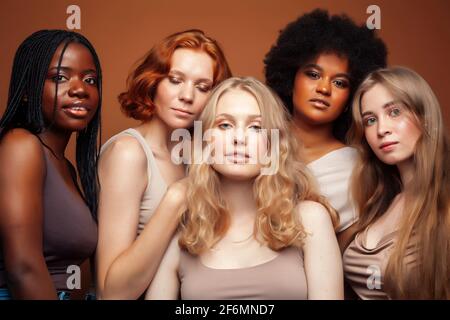 Junge hübsche kaukasische, afro, skandinavische Frau posiert fröhlich zusammen auf braunem Hintergrund, Lifestyle diverse Nationalität Menschen Konzept Stockfoto