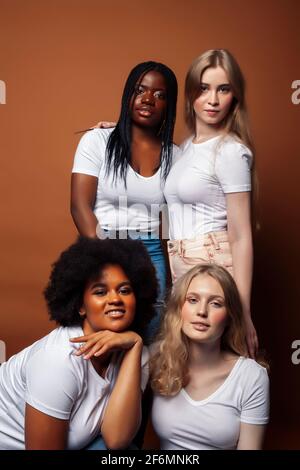 Junge hübsche kaukasische, afro, skandinavische Frau posiert fröhlich zusammen auf braunem Hintergrund, Lifestyle diverse Nationalität Menschen Konzept Stockfoto
