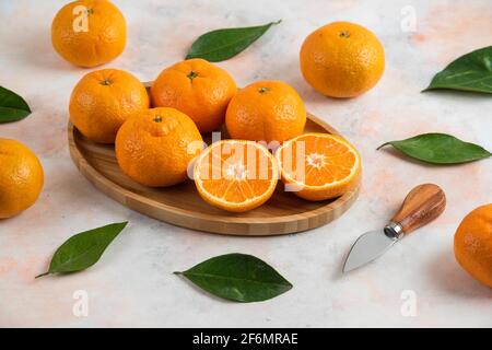 Clementine Mandarinen und Blätter auf Holzplatte Stockfoto