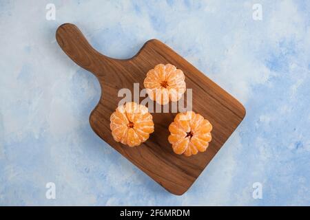 Drei frisch geschälte Mandarinen auf Holzschneidebrett. Draufsicht Stockfoto